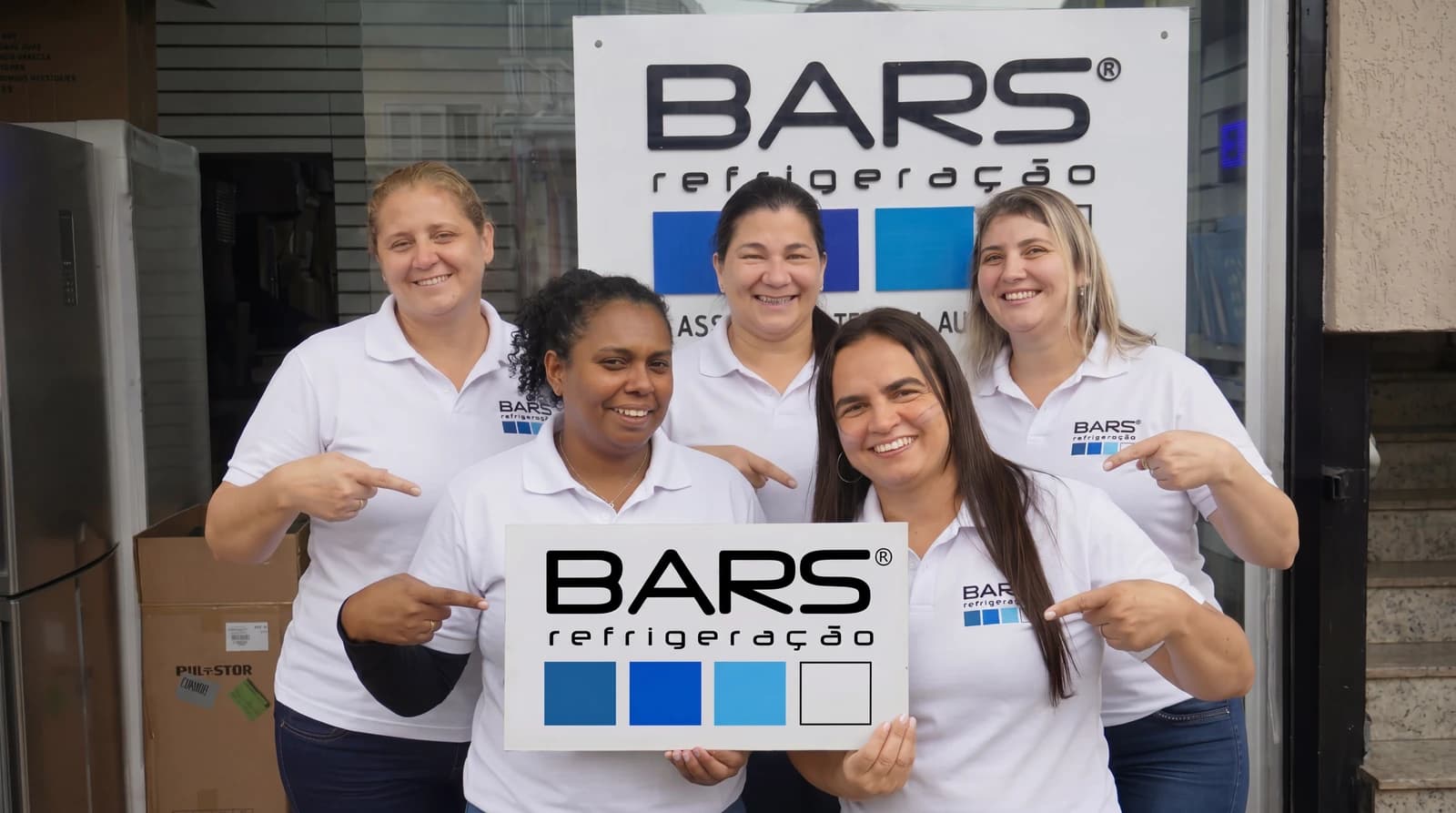Equipe da Refrigeração Bars reunida na entrada da loja, com a identificação Bars ao fundo